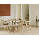 The Round Geometric Dining Table in Oak from Ethnicraft in a dining room with upholstered Bok Dining Chair and Osso dining stool.