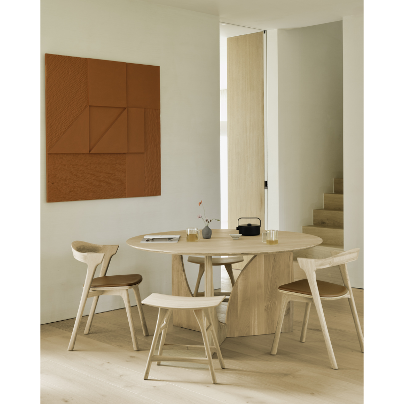 The Round Geometric Dining Table in Oak from Ethnicraft in a dining room with upholstered Bok Dining Chair and Osso dining stool.