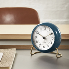 The Station Alarm Clock from Arne Jacobsen in petrol blue in a workspace.