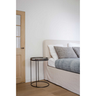 The Tray Side Table from Ethnicraft beside a bed in a bedroom.