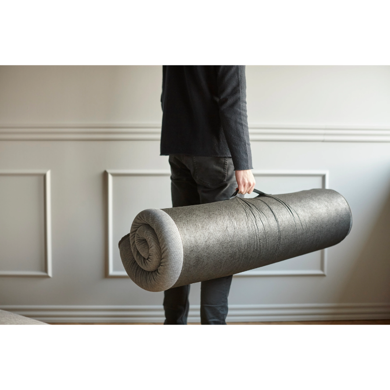 The Full Size Mattress Pillow Topper from Innovation Living in a lounge rolled up in a lifestyle photograph.