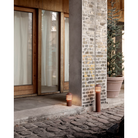 The tall Bysted Garden Bollard from Louis Poulsen in an outdoor lounge.