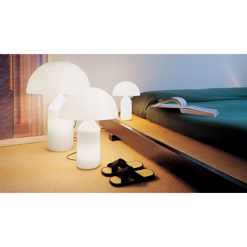 The Atollo Glass Table Lamp from Oluce in a bedroom.