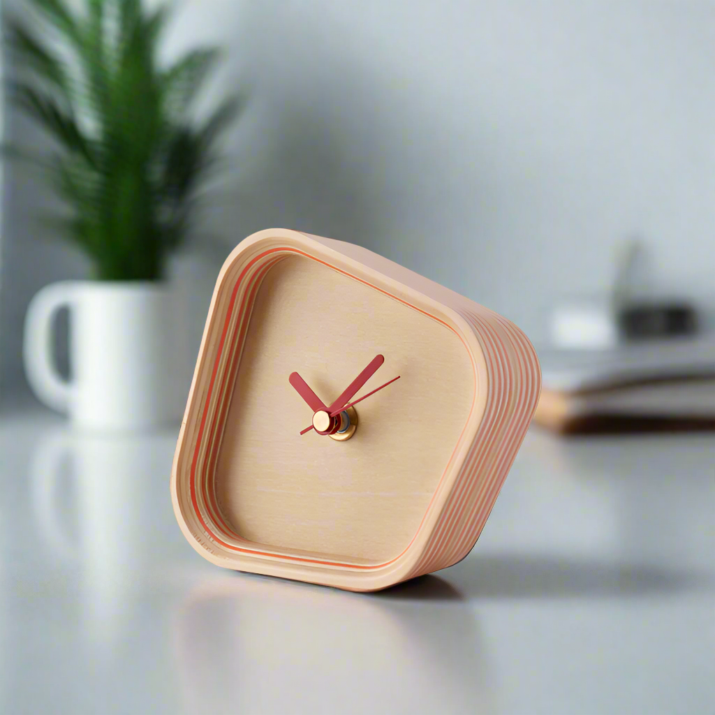 The Rotation Clock from Plywood Laboratory in orange on a desk.