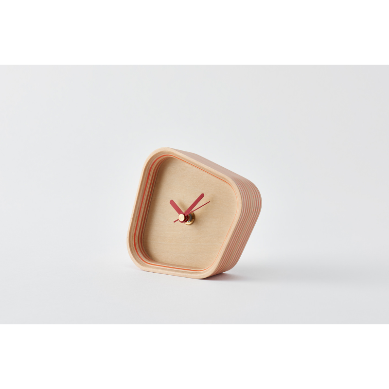 The Rotation Clock from Plywood Laboratory in orange in a studio.