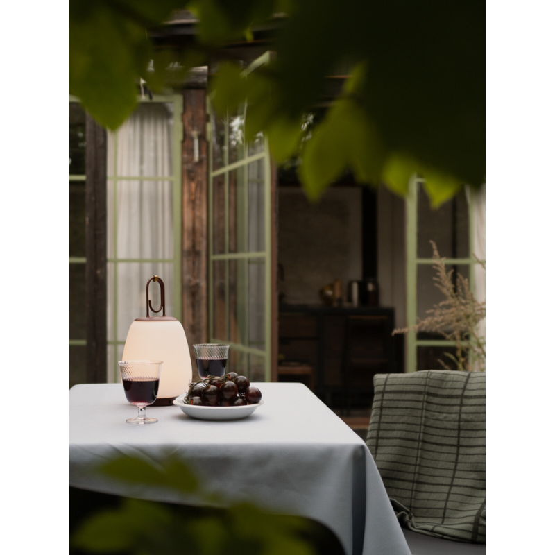 The Lucca Portable Lamp from &Tradition in an outdoor dining scenario.