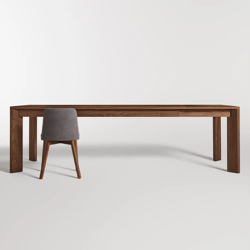 The 80 to 104 inch Moreover Extension Dining Table from Blu Dot in walnut extended in a studio.