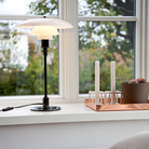 The PH 3/2 Glass Table Lamp from Louis Poulsen on a windowsill.