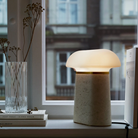 The Nova Table Lamp by Woud in ivory travertine with an opal glass shade in a living room.