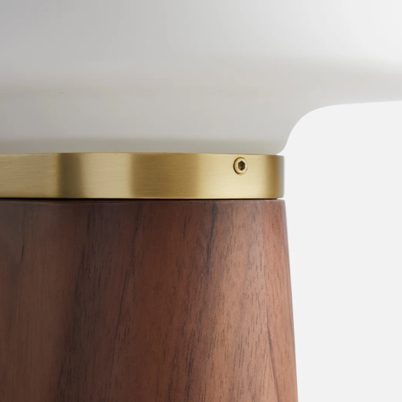 The Nova Table Lamp by Woud in walnut in a detailed image of the opal shade and brass detailing.