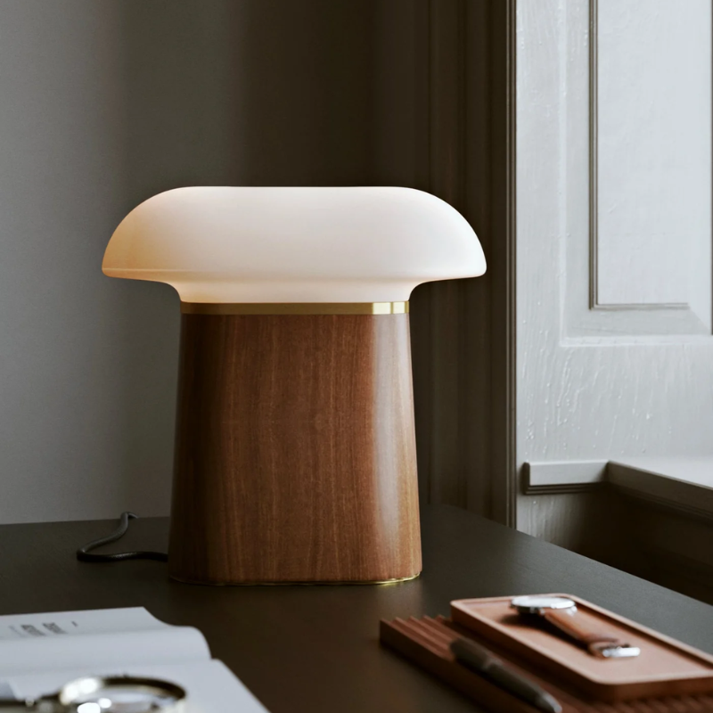 The Nova Table Lamp by Woud in walnut with an opal glass shade in a study.