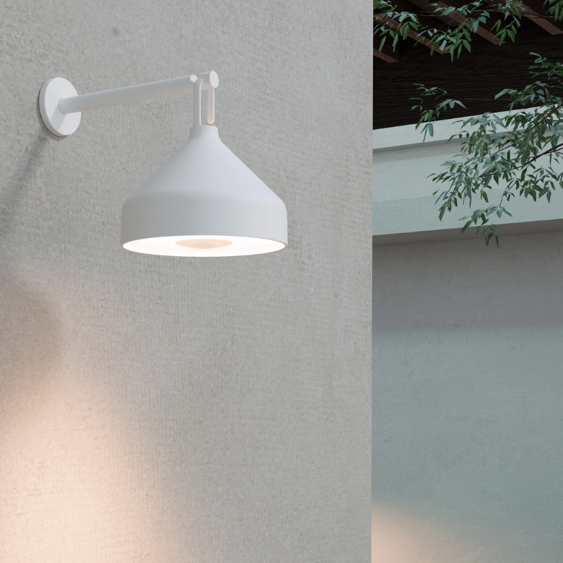 The Amelie Pro Wall Lamp from Zafferano outdoors in a garden.